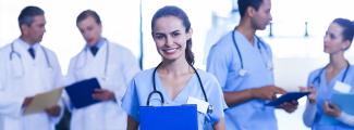 female nurse smiling colleagues in background - enfermera sonriendo y colegas al fondo